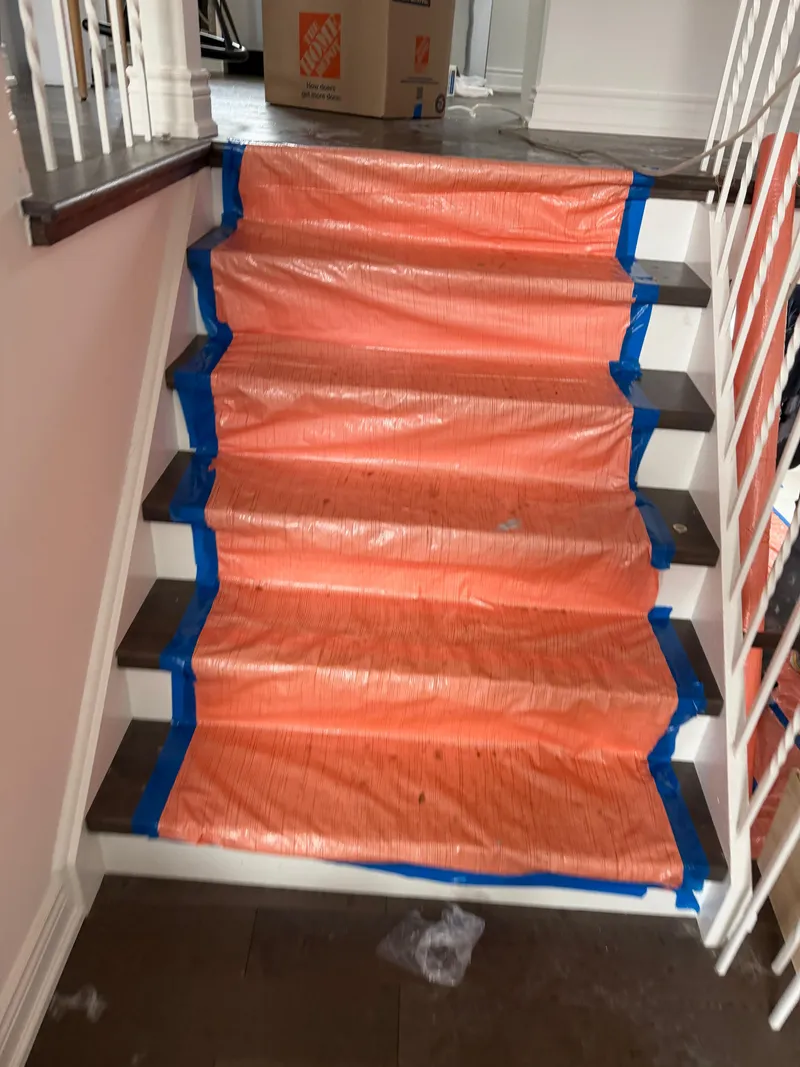 Orange ram board and blue painter's tape protecting a hardwood staircase during restoration